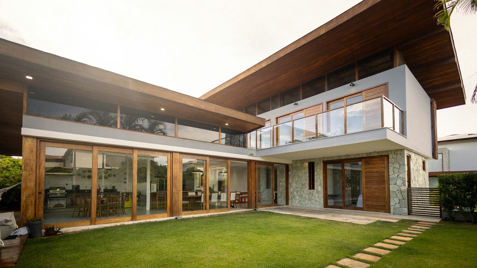 Finished modern home with glass walls and a green lawn